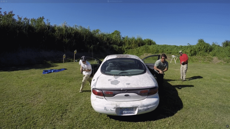 Two students move around a car during an outdoor vehicle tactics drill.